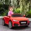 A young girl is sitting in a red toy car outdoors. Produktbild-Vorschau