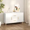 A white sideboard with wooden legs and handles, decorated with a painting and small decorative items, placed on a wooden floor next to a plant and curtains. Produktbild-Vorschau