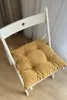 A yellow seat cushion on a white folding chair. Produktbild-Vorschau