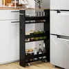 A narrow black shelving unit with wooden top, filled with jars and bottles, placed between a white cabinet and a refrigerator. Produktbild-Vorschau