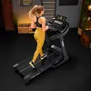 A woman is running on a treadmill in a home gym setting. Produktbild-Vorschau