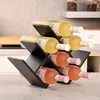 A black wine rack holding six bottles of wine, with two bottles of white wine on top and four bottles of rosé wine below, on a countertop. Produktbild-Vorschau