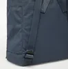 A close-up view of the bottom corner of a dark blue backpack, showing the strap and buckle. Náhled obrázku produktu