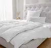 A white down and feather comforter is neatly spread on a bed with a tufted headboard. Produktbild-Vorschau