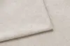 A close-up view of a cream-colored fabric, folded to show its texture. Náhled obrázku produktu