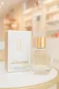 A perfume bottle and its box are displayed on a table with a blurred background of a store. Produktbild-Vorschau
