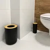 A bathroom corner with a toilet, trash can, and toilet brush holder. Voir les images du produit