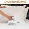 A person's hands are shown adjusting a white pillow on a bed, with a small white device placed on the bedsheet in the foreground. Podgląd zdjęcia produktu