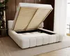 A cream-colored upholstered bed with its storage compartment open, revealing the slatted base and storage space underneath. The bed is in a bedroom setting with wooden wall paneling and curtains in the background. Náhľad obrázku produktu