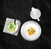 A top-down view of two plates of food and a creamer jug on a dark, textured surface. Anteprima dell’immagine prodotto