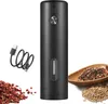 A black electric pepper grinder with a USB charging cable and a pile of peppercorns and other spices. Náhľad obrázku produktu