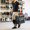 A man is carrying a stack of toolboxes in a workshop or storage area. Náhled obrázku produktu