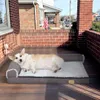 A corgi dog is lying on a dog bed on a wooden porch. Náhľad obrázku produktu
