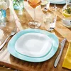 A table setting with plates, glasses, and cutlery on a wooden table. Anteprima dell’immagine prodotto