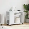 A white side table with shelves and wheels, decorated with vases and books, placed in a room next to a sofa and a large plant. Podgląd zdjęcia produktu