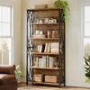 A tall, industrial-style bookshelf filled with books and decorative items, placed in a living room setting next to a window and a leather armchair. Náhled obrázku produktu