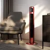 A red tower fan is positioned next to a chair and a dresser. Náhled obrázku produktu