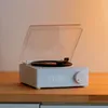 A white record player with a clear lid, sitting on a wooden surface. Podgląd zdjęcia produktu