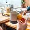 Keramiktasse "Climbing Mug Evo" von YY Vertical mit Klettergriff; in einer Hand gehalten; auf einem Tisch. Podgląd zdjęcia produktu
