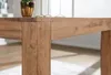 A close-up view of a wooden table leg and tabletop, with decorative items in the background. Anteprima dell’immagine prodotto