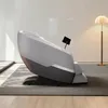A modern massage chair is shown in a well-lit room with a floor lamp in the background. Produktbild-Vorschau