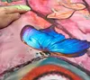 A close-up of a fabric with a butterfly print, with a hand touching the fabric. Produktbild-Vorschau