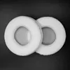 Two white circular ear pads are shown on a black background. Náhled obrázku produktu