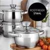 A set of stainless steel pots with glass lids on a kitchen counter, with tomatoes in the foreground. Náhled obrázku produktu