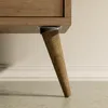 A close-up view of a wooden furniture leg attached to a cabinet. Náhled obrázku produktu