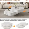 A white rotating coffee table is shown in a living room setting with a couch in the background. Voir les images du produit