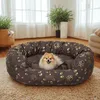 A small dog is resting in a comfortable, oval-shaped dog bed with a paw print pattern. Podgląd zdjęcia produktu