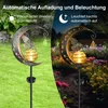 A garden solar light shaped like a crescent moon with a fairy and a glowing orb, shown in both daylight and nighttime settings. Produktbild-Vorschau