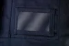 A close-up view of a dark blue fabric with a clear plastic window pocket, likely part of a garment like work pants or a jacket. Náhled obrázku produktu