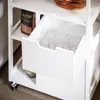 A close-up view of a white kitchen cart with a drawer partially open, revealing glasses inside. A bag of pasta is visible on the shelf above. Náhled obrázku produktu
