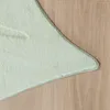 A close-up view of a light green rug with a textured surface, placed on a light brown wooden floor. Produktbild-Vorschau