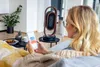 A woman is using her smartphone to control a fan heater in a living room. Podgląd zdjęcia produktu