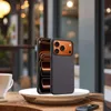 A smartphone case is displayed on a plate on a wooden table, with a coffee cup in the background. Produktbild-Vorschau
