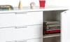 A white sideboard with drawers and an open cabinet filled with books and magazines. Produktbild-Vorschau