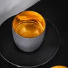 A close-up shot of an espresso cup with a gold interior, placed on a black saucer. Náhled obrázku produktu