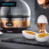A close-up shot of a copper and black egg cooker with two halves of a hard-boiled egg in the foreground. Produktbild-Vorschau