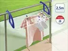 A clothes drying rack is attached to a balcony railing, with clothes hanging on it. Náhled obrázku produktu