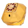 A close-up, angled view of a gold-colored perfume bottle with red jewel accents on the cap. Náhled obrázku produktu