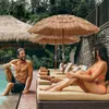 A couple relaxing by a pool under thatched umbrellas. Náhled obrázku produktu