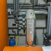 A close-up view of a heating and cooling system's control panel and plumbing. Produktbild-Vorschau