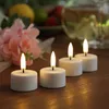 Four LED tea lights are arranged on a wooden surface, with a bouquet of pink flowers and some fruit in the background. Produktbild-Vorschau