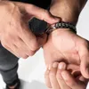 A person is fastening a bracelet on their wrist. Anteprima dell’immagine prodotto