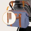 A blue diaper bag with brown accents is shown hanging from a stroller handle. An inset circle shows three different strap lengths. Náhľad obrázku produktu