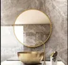 A modern bathroom vanity with a round gold-framed mirror above a gold basin sink and a brass faucet. Podgląd zdjęcia produktu