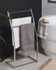 A modern bathroom setting with a freestanding towel rack holding towels next to a bathtub. Náhled obrázku produktu