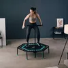 A woman is exercising on a trampoline in a room. Voir les images du produit